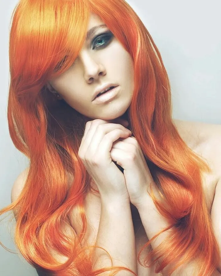 Femme rousse nue, regardant l'appareil photo, mains jointes près du visage, sur fond clair