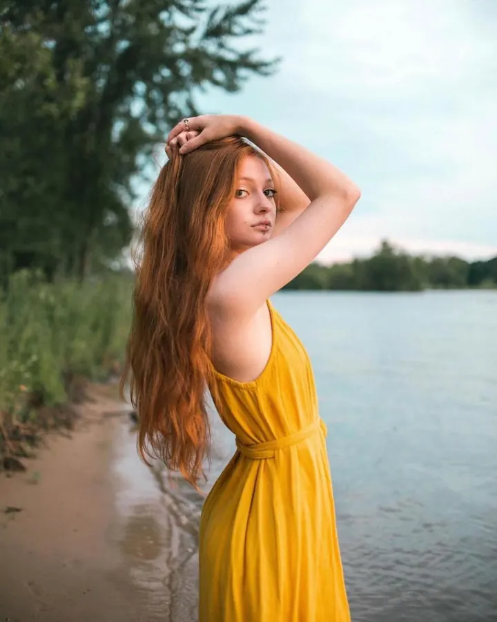 Femme nue de dos, vue de profil, portant un string noir, debout près d'une fenêtre